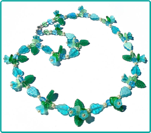 A custom floral necklace of aqua and green flower and leaf beads.